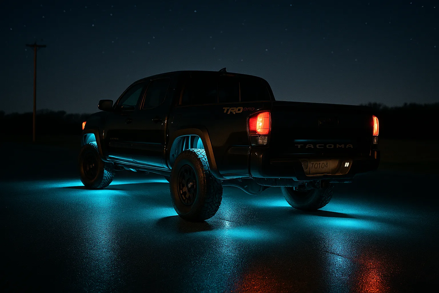 Toyota Tacoma at night with cyan rock-light beams under each wheel well